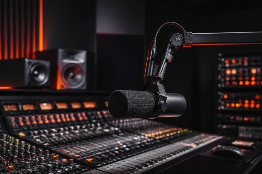 Microphone de studio sur bras articulé dans une régie sombre éclairée d'orange