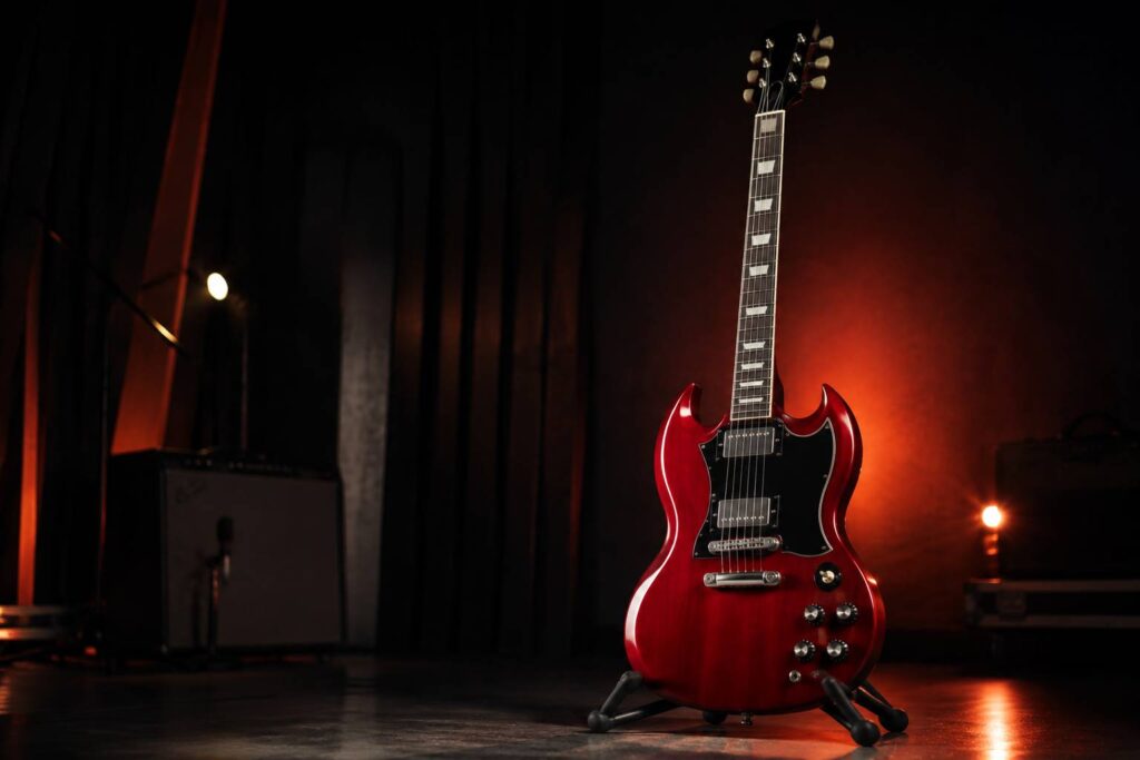 Guitare électrique à double pan coupé rouge cerise sans logo posée dans un studio sombre